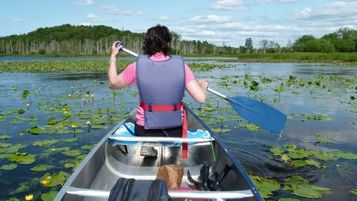 Rear view of senior woman standing on lake against sky