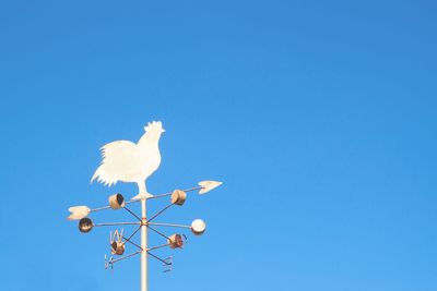 Low angle view of birds perching on blue sky