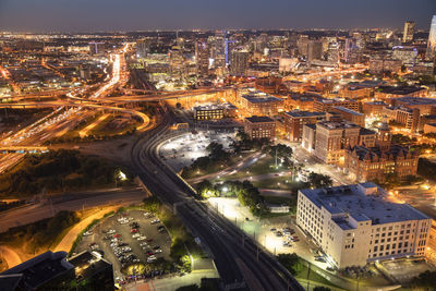 High angle view of illuminated street amidst buildings in city at night