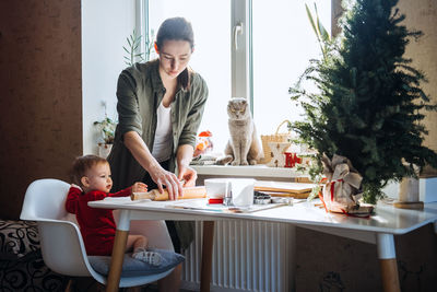 Happy mother and little baby toddler girl making christmas cookies in home kitchen. mother and