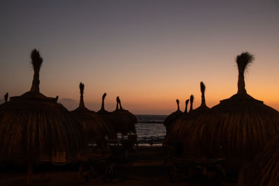 Silhouette people on beach against clear sky during sunset