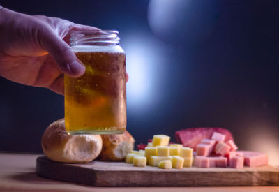 Cropped hand having beer with food at table