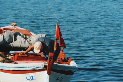 Rear view of men sitting on boat sailing in sea