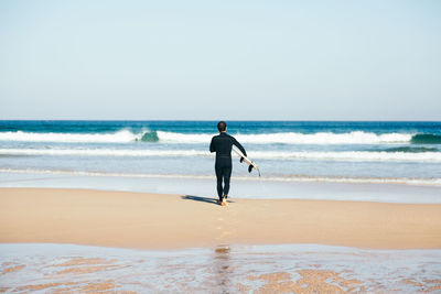 Full length of man on beach against clear sky