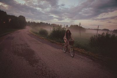 Women riding bicycle on road against sky