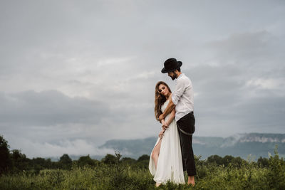 Full length of young couple standing on field