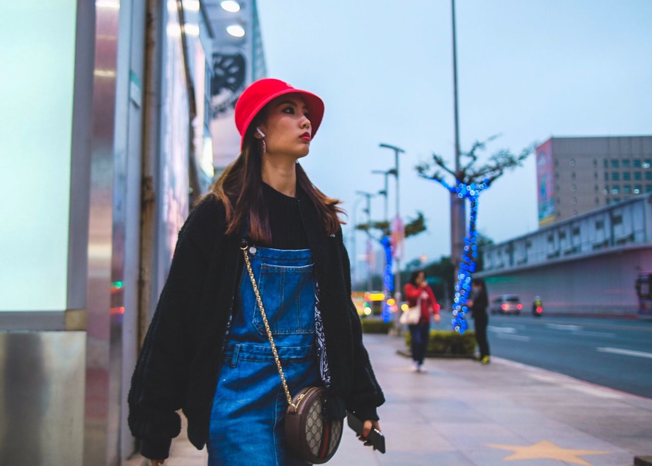 one person, standing, young adult, architecture, lifestyles, city, casual clothing, front view, young women, building exterior, focus on foreground, real people, looking, leisure activity, looking away, built structure, waist up, women, beautiful woman, outdoors, hairstyle, contemplation