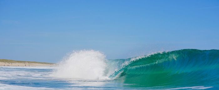 Water splashing in sea against clear blue sky