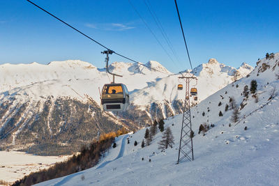 Ski lift over snowcapped mountains against sky