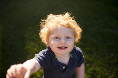 High angle portrait of cute baby boy standing on grassy field at yard