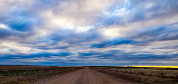 Road amidst field against sky