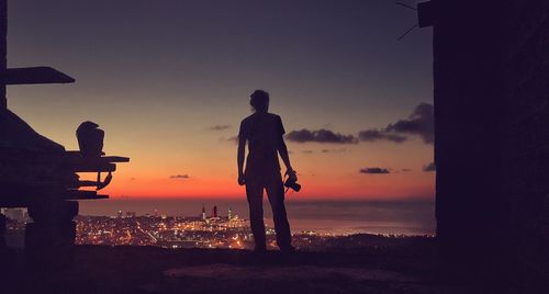 Silhouette people looking at sea against sky during sunset
