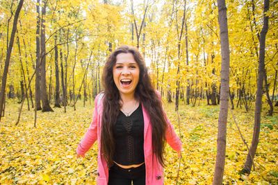 Happy young woman standing in forest during autumn