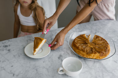 Close up of mother's hands putting a piece of apple pie on a plate for breakfast in the morning