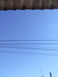 Low angle view of cables against clear blue sky