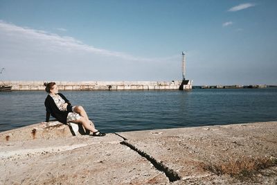 Full length of woman sitting at promenade against sky