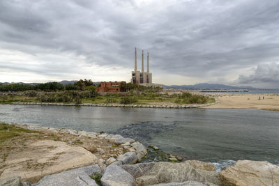 Built structure by river against sky