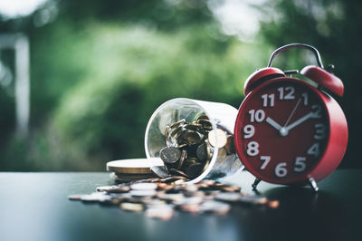 Coins spilling by alarm clock on table