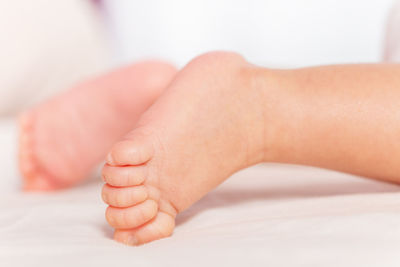 Cropped hands of baby on bed