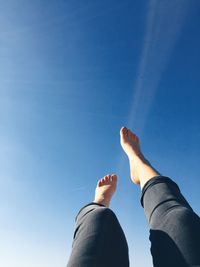 Low section of woman against blue sky