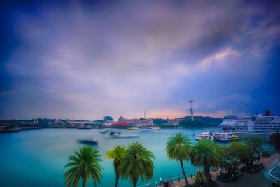 Boats moored at harbor against cloudy sky