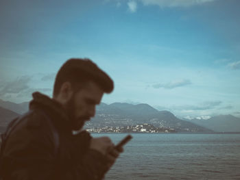Close-up of man using phone against sky