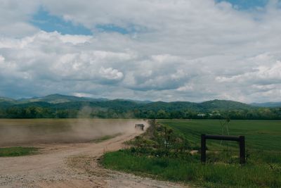 Road amidst field against sky