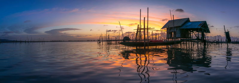 Sailboats moored on sea against sky during sunset