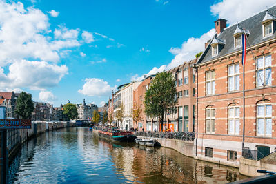 Canal amidst buildings in city against sky