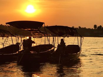 Silhouette people in boat on sea against sky during sunset