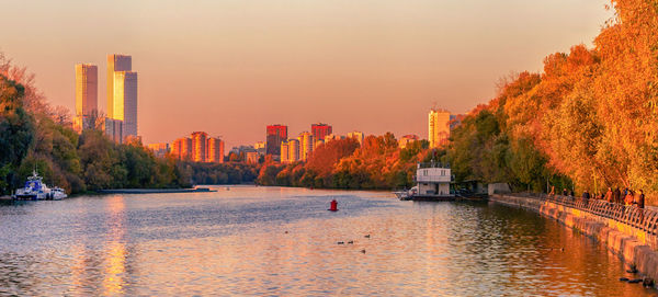 Buildings by river against sky
