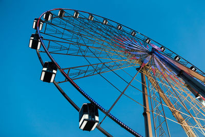 Low angle view of ferris wheel against clear blue sky