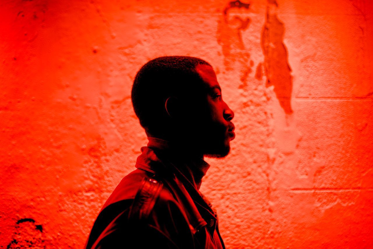 SIDE VIEW OF A MID ADULT WOMAN AGAINST RED BACKGROUND