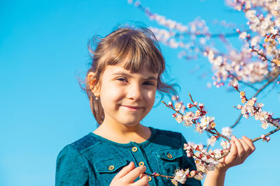 Portrait of smiling girl with flower under blue sky