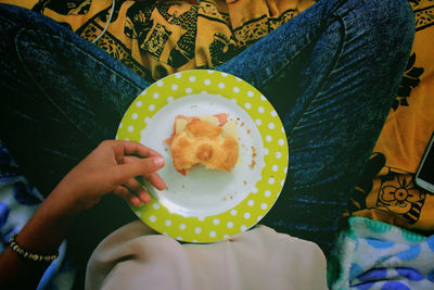 Low section view of woman holding cookie in plate 