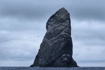 Rock formation in sea against sky