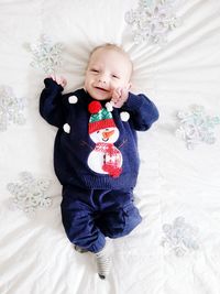 Portrait of cute baby boy lying on bed at home with  winter surroundings.