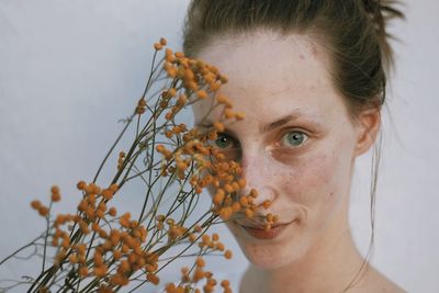 Portrait of woman holding flowering plant against white background