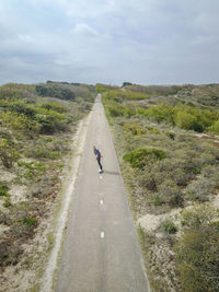 A man with long hair skating on a empty road in europe