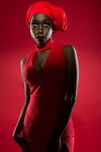 Young woman wearing dress standing against red background