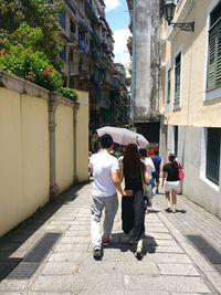 Rear view of people walking on street amidst buildings