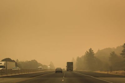 Cars on road against sky during sunset