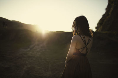 Rear view of woman standing on mountain against sky