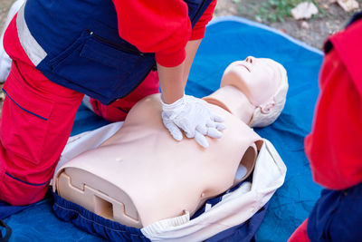 Midsection of person practicing cpr on dummy outdoors