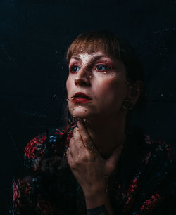 Portrait of beautiful young woman against black background