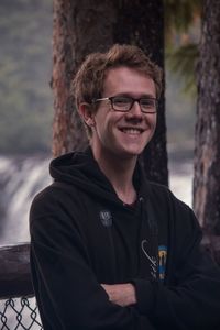 Portrait of smiling young man against tree trunk