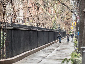 People walking on footpath amidst bare trees