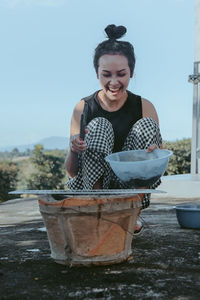 Portrait of smiling young woman holding potted plant