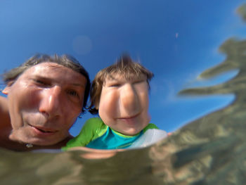 Father with daughter reflecting in water at beach