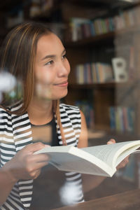 Smiling woman looking away while holding book